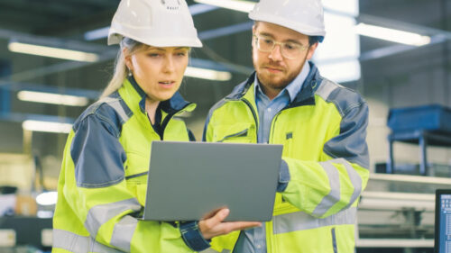 two maintenance professionals reviewing data from a laptop
